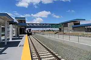 A railway platform in the middle of a highway, with a footbridge leading to one side of the highway