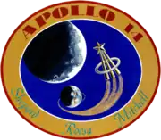 The circular patch depits the Earth and the Moon. An astronaut lapel pin leaves a comet trail from the liftoff point on Earth. Around it is the logo "Apollo 14 – Shepard Roosa Mitchell"