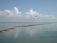 Aerial photograph of a bay and islands with a paramotoring figure