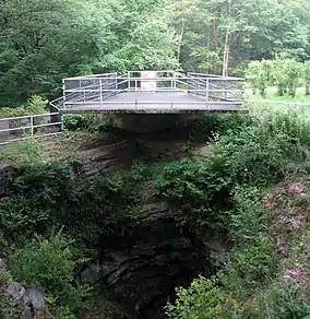 A platform with a fence around it above a deep rocky hole