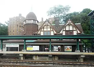 A view of an ornate structure with railroad tracks and a modern elevated platform and metallic structure in the foreground