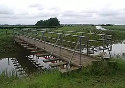 A Bailey Bridge over a Beck, which is surrounded by green fields