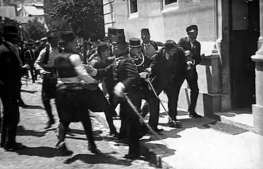 Group of gendarmes dragging a man towards a building.