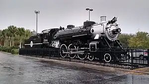 A black steam locomotive with a 4-6-2 wheel arrangement (four leading wheels, six driving wheels, and two trailing wheels) and its tender