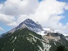 A rocky pyramid-shaped mountain peak with forested lower slopes.