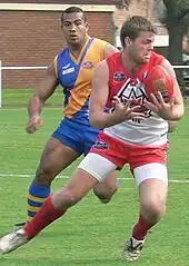 Canadian Aussie Rules player evades Nauruan opponent at 2008 International Cup.