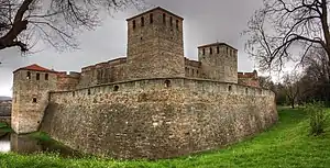 Photograph of a medieval stone castle with two rectangular towers in the foreground