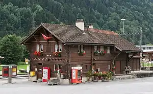 Two-story wooden building with gabled roof next to double-track railway line