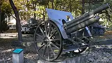 An artillery piece mounted on a concrete platform in a park