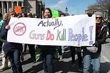 Three people carrying a banner