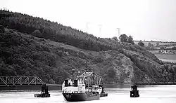 A boat passing through the opening of Barrow Bridge with 3 tug boats helping