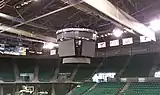 Arena scoreboard hanging in an empty venue with banners and seats visible