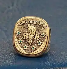 A gold ring with the words quote ring of honor" at the top six stars with jewelsin the symbol of the New York Liberty in the center