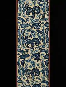 This curtain panel is worked in crewel embroidery in shades of blue. The design is a variety of types of stylized leaves.