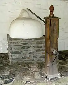 A beehive oven and a water pump on the side porch of the Wall House