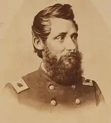 Sepia-toned photo shows a heavily-bearded man wearing a dark uniform with two rows of buttons.