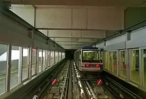 Boxy metro vehicle on track at station with platform doors