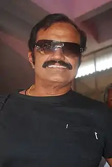 Raghu smiling, wearing a black T-shirt and sunglasses