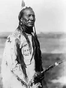 Native American Big Mouth Spring with decorated scalp lock on right shoulder. 1910 photograph by Edward S. Curtis.