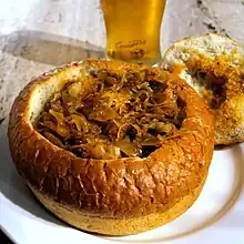 Bigos (hunter's stew) served in a bread bowl with a glass of beer at a restaurant in Kraków