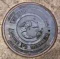 Manhole cover, San Antonio. English, except "No Basura!" ('No trash/waste!') in Spanish. "Made in India" in English