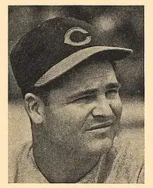 A man wearing a baseball cap with a "C" on the front looks–the right, squinting.