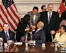 Wes Moore shakes Ivan Bates's hand after signing his bill to strengthen sentences for illegally carrying handguns