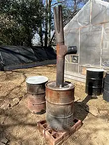 Biochar (charcoal) is produced in this double burn barrel.  Chunks of woody biomass are placed within an inner barrel, feedstock to "cook" the inner biomass is placed around the inner barrel, and then the feedstock is ignited.  This converts the woody biomass into almost pure carbon.  The carbon biochar is then used to amend compost.  This sequesters carbon, and provides a good home more microbes in the soil.  Some advanced biochar units can capture the heat for heating homes, water, air, and even produce electricity with the aid of a stirling engine.