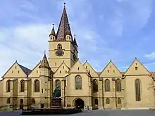 A church with a high tower and with smaller parts covered with triangular roofs