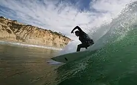 A surfer at Black's, with cliffs in background