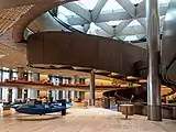 Interior of an office building with a large spiral bronze coloured ramp between floors