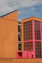 An orange brick building with pink window frames and a blue roof