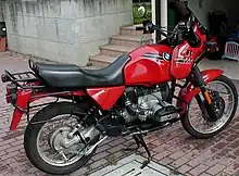 Red BMW R80GS parked on a driveway with some steps and an open garage door in the background