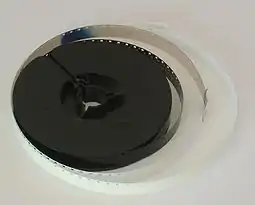 A spool of developed Super 8 Film, with a protective white leader.