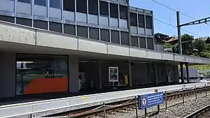 Single-story building with flat roof next to double track