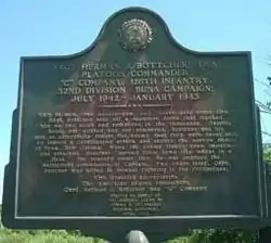 The memorial plaque at the entrance to Buna Village, dedicated to Herman Bottcher and the 32nd Red Arrow Division Infantry Division.