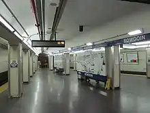 A wide subway platform with white columns