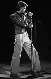 A black and white photograph of a man singing into a microphone