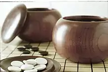 Image 14An example of single-convex stones and Go Seigen bowls. These particular stones are made of Yunzi material, and the bowls of jujube wood. (from Go (game))