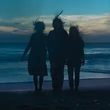 Three silhouettes of women standing on the beach