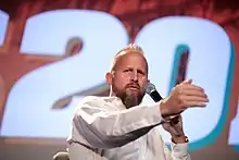 Parscale holding a microphone and standing at a lectern