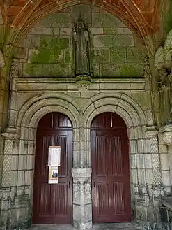 The double doored entrance to the church and the statue of Jesus giving a blessing whilst holding a globe