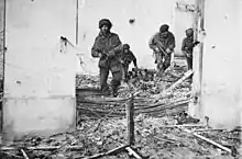 Four men in bombed building walking over rubble