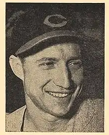 A man wearing a dark baseball cap with a "C" on the center smiles and looks–the right.