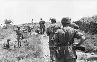 a black and white photograph of three allied soldiers surrendering to four German paratroopers