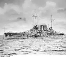 A battleship at sea with a smaller boat alongside