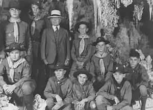 Photograph of Burnham in 1941 celebrating his 80th birthday with several Boy Scouts.  All of them are posing in Carlsbad caverns. The boys are dressed in their Boy Scout uniforms.  Burnham is dressed in a full suit and tie and wearing a white hat.