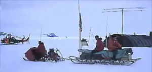 Sleds pulled by snowmobiles or dogs provided transportation between campsMcMurdo Station right background (around 1960).