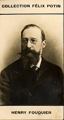 white man in middle age with still mostly dark hair, receding slightly, a large moustache and neat beard; he is wearing pince-nez glasses