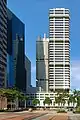 Distant view of a box-like building with many black ridges; a similar-looking building is located directly behind it.